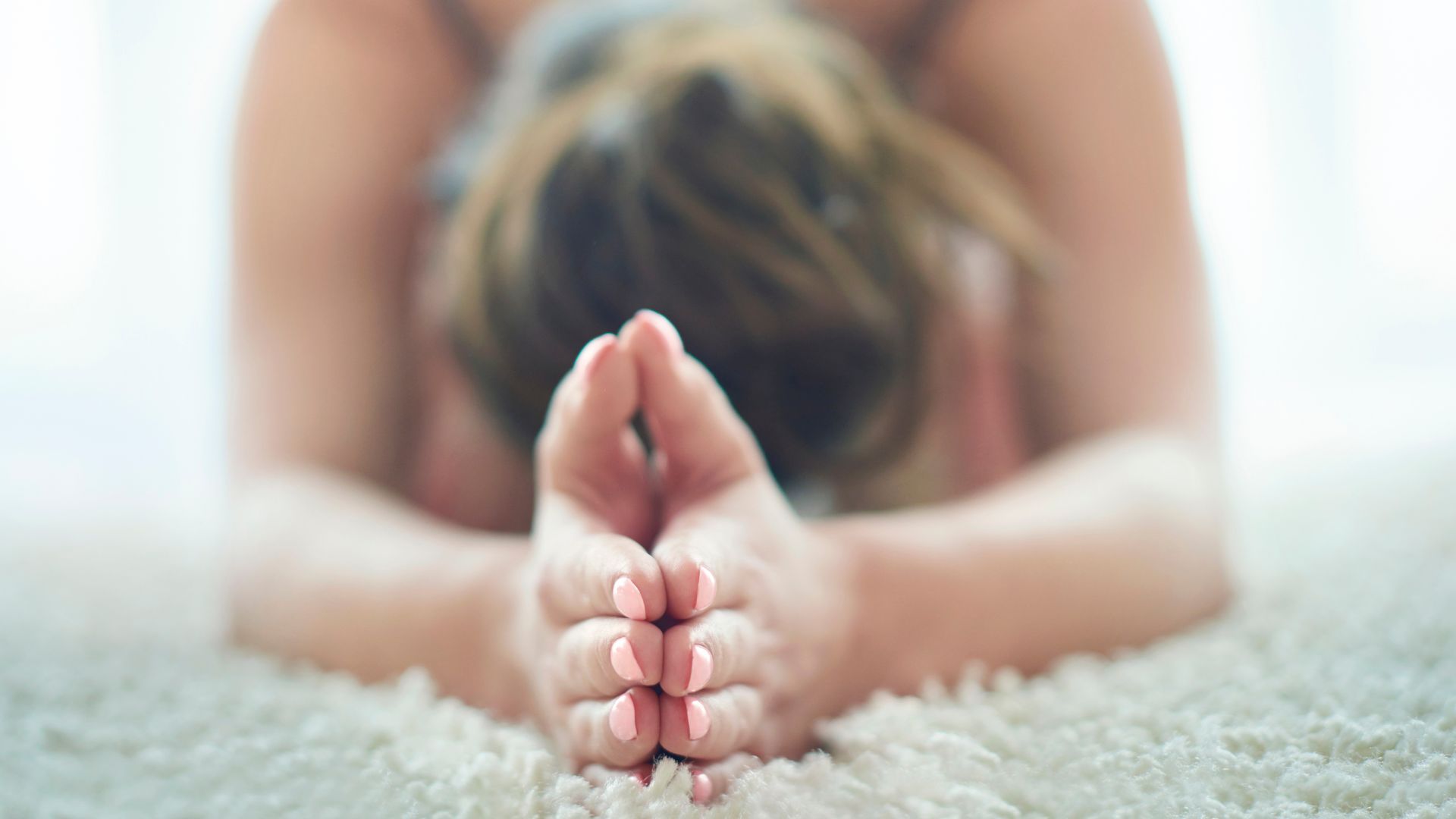 kvinna som göra yoga med rosa naglar